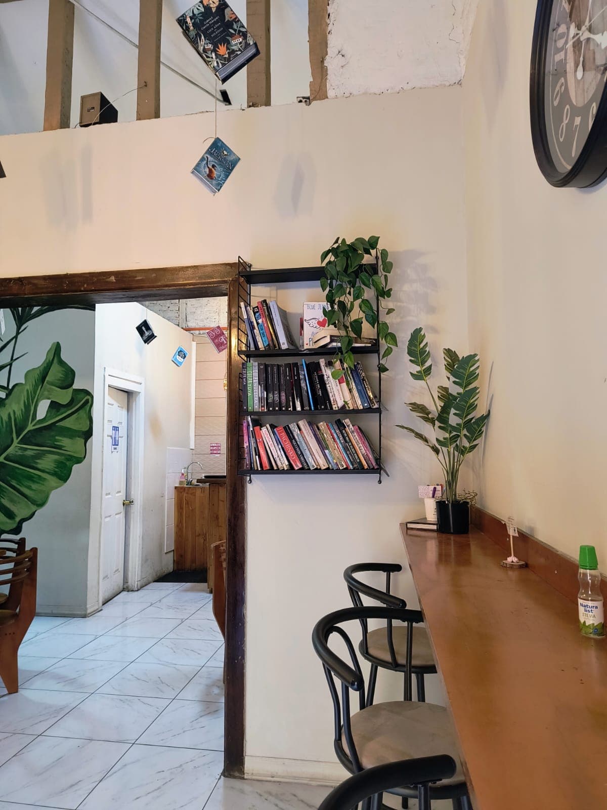 Librero con novelas junto a la barra de ventana y libros colgantes